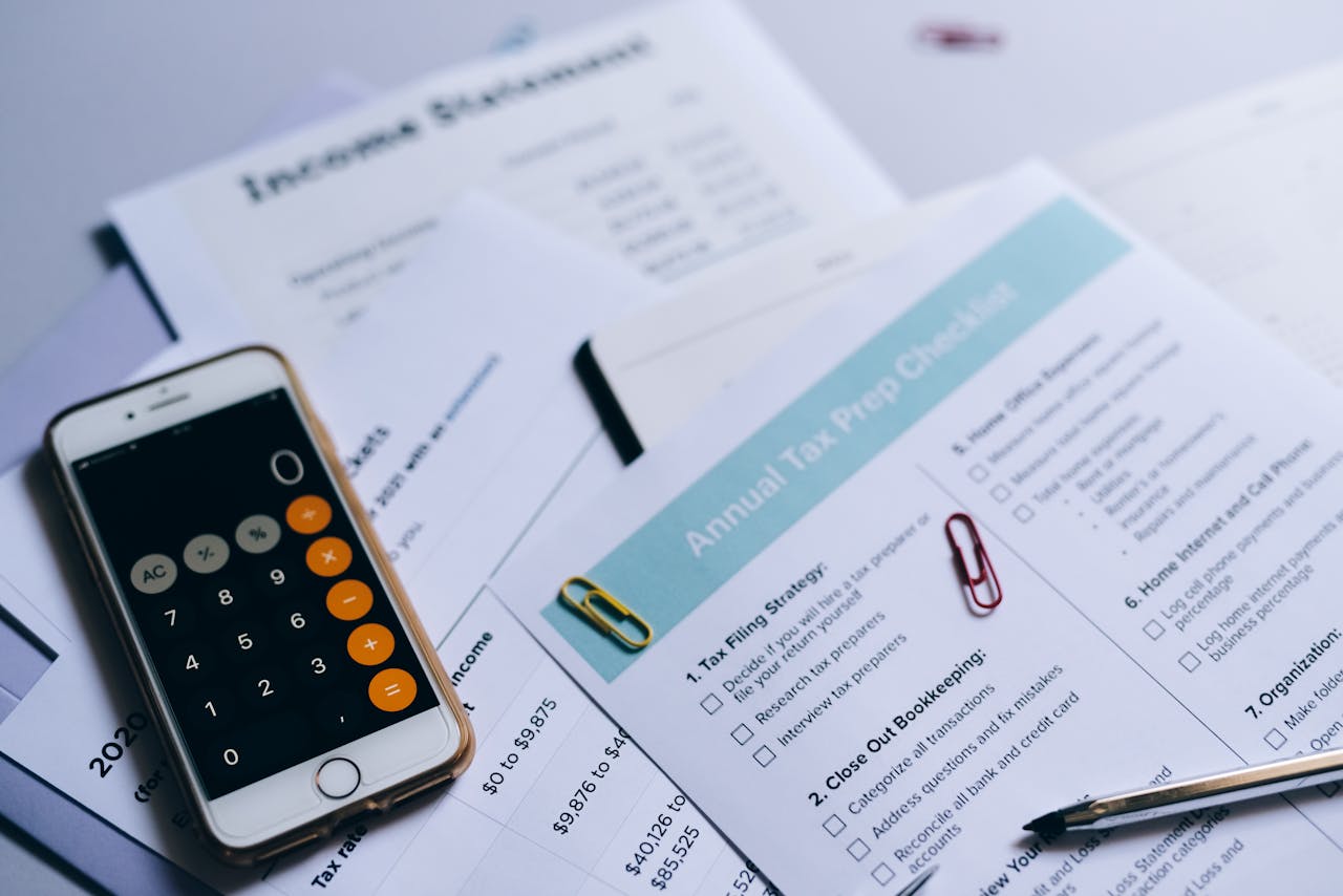 heros-img Tax preparation setup with documents, smartphone calculator, and checklist.